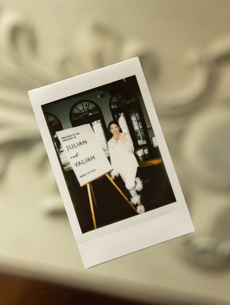 Polaroid of bride in front of wedding sign