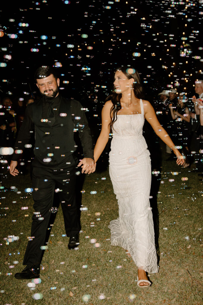 bride and groom walking through bubble wedding exit