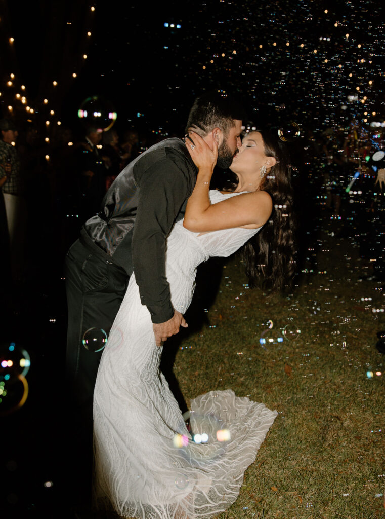 bride and groom kissing in bubble wedding exit