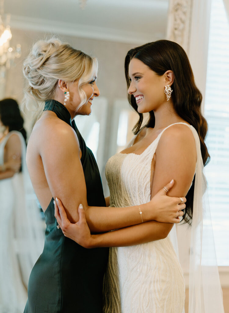 bride and maid of honor hugging and smiling