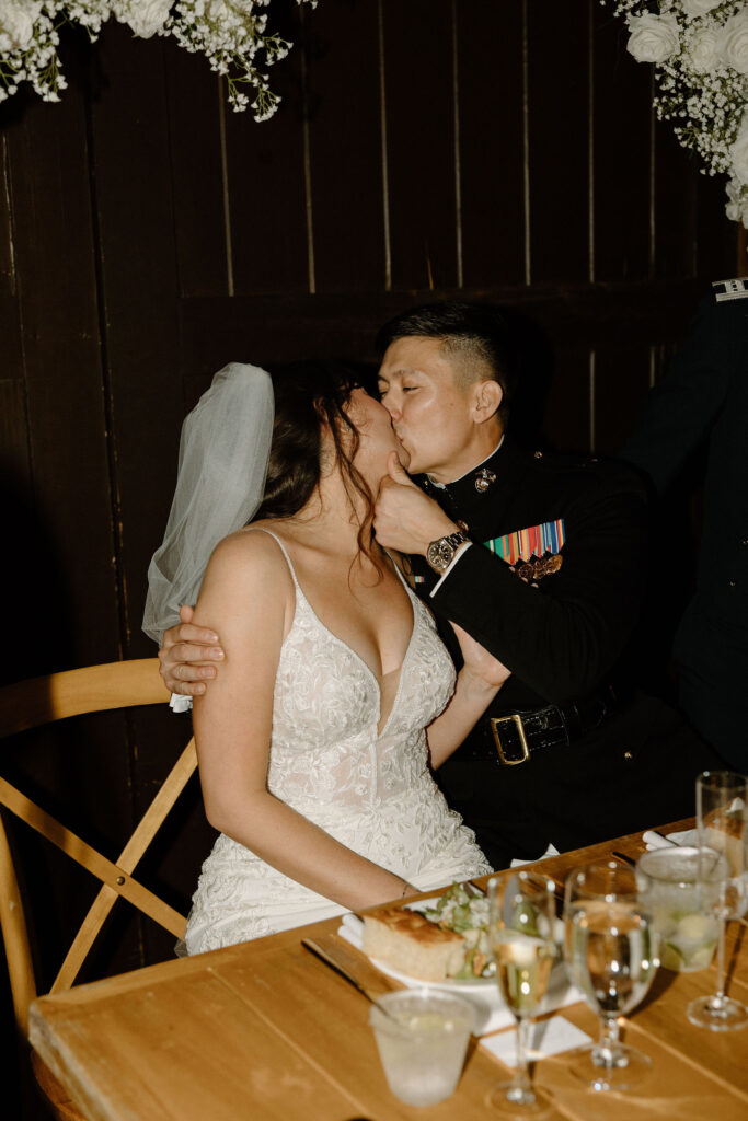 bride and groom kissing at reception table