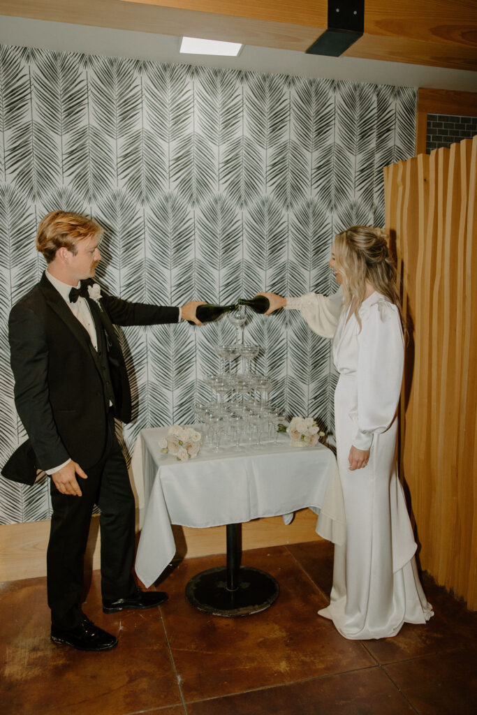 bride and groom pouring champagne tower at wedding reception at the view at st. joe bay venue