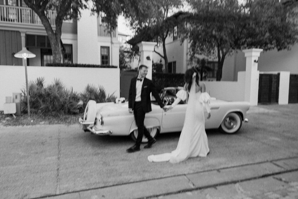 candid black and white blurry elopement photos bride and groom walking in front of vintage car
