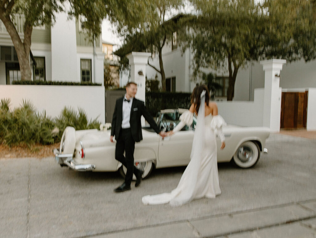 candid blurry elopement photos bride and groom walking in front of vintage car