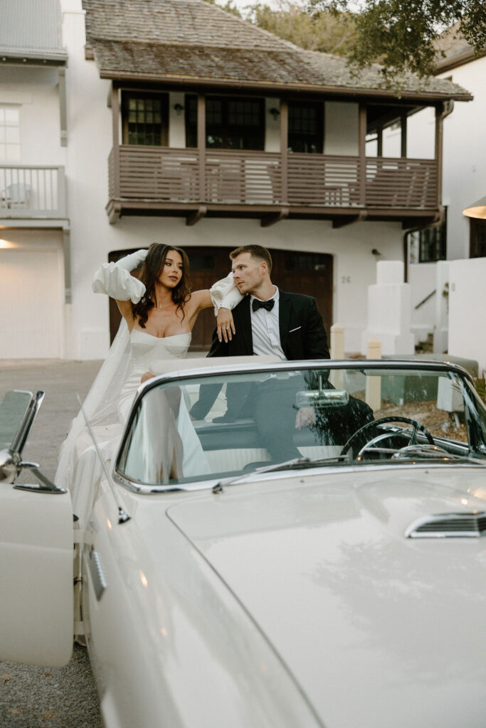 bride and groom posing on vintage car for elopement in florida rosemary beach 30A