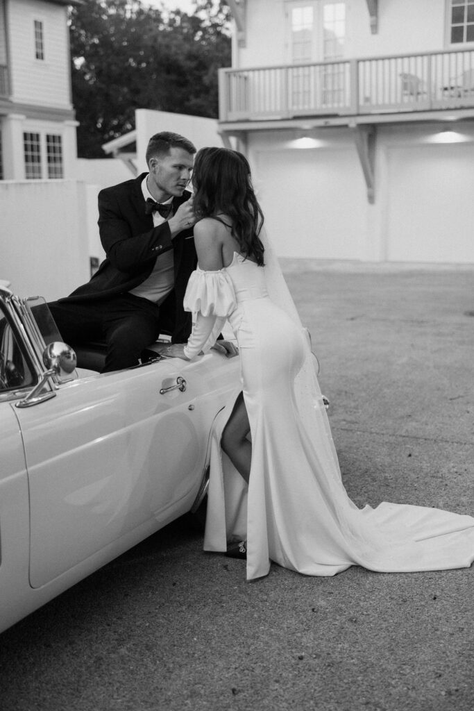 bride and groom posing on vintage car for elopement in florida rosemary beach 30A