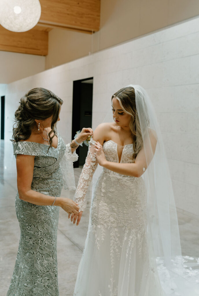 mother of bride helping bride get ready for ceremony photos